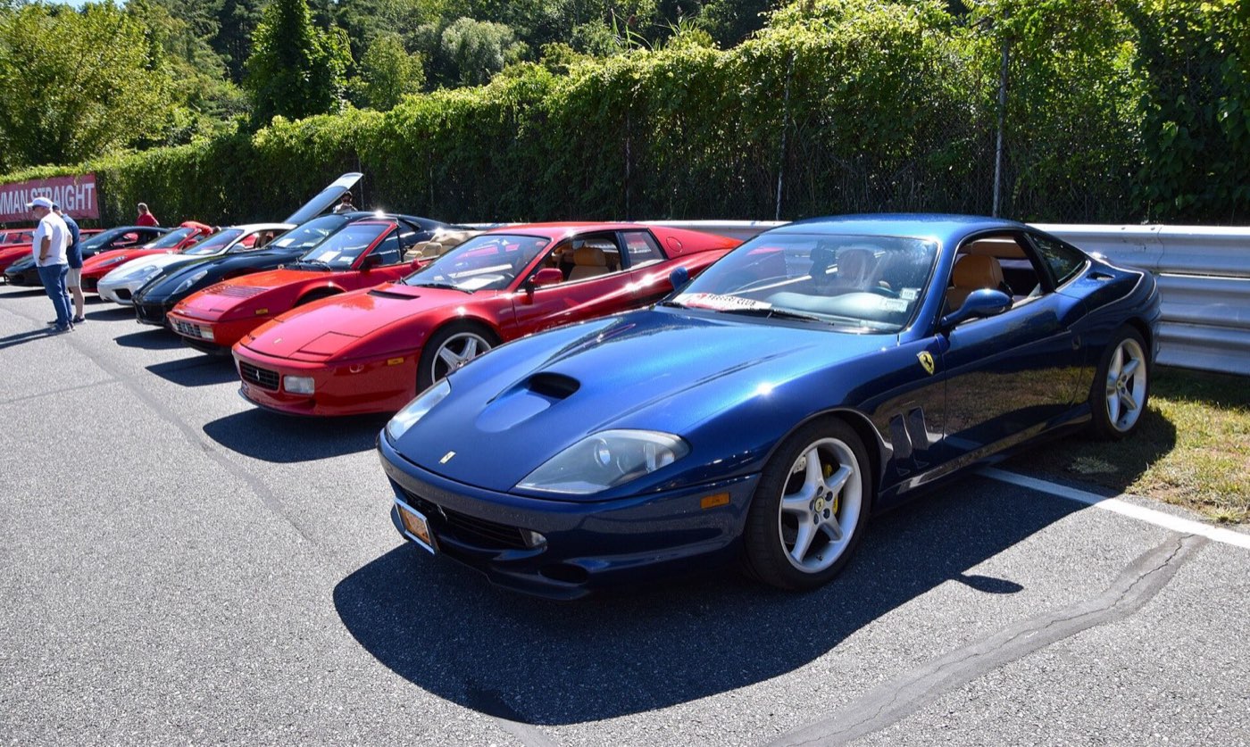 A row of Ferrari 550 Maranellos in blue and red lined up at a car show