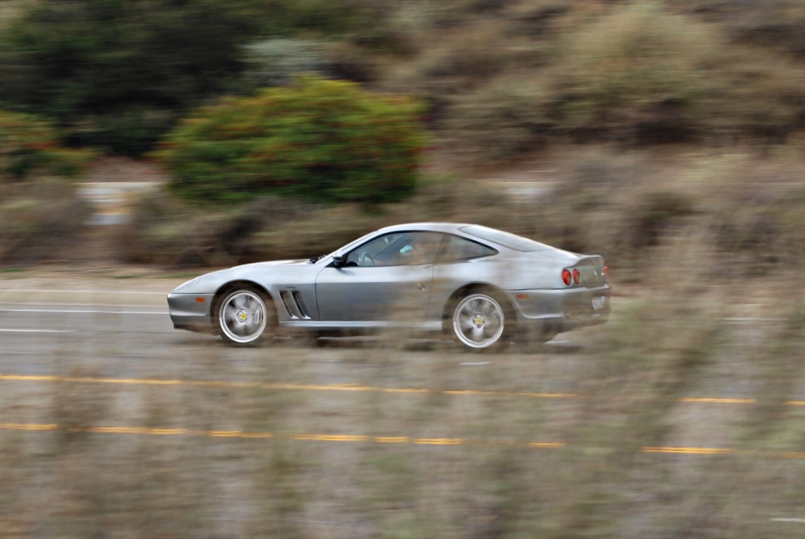 Silver Ferrari 550 Maranello at speed on an open road, panned motion blur
