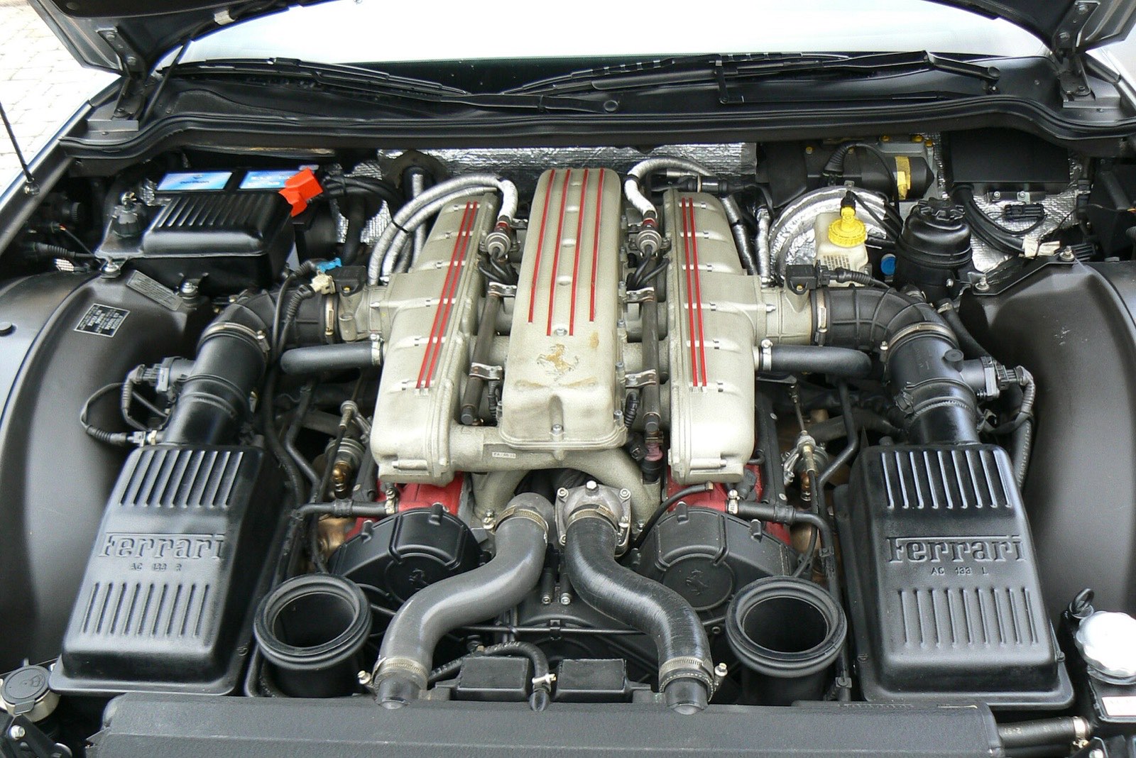 Ferrari 550 Maranello engine bay showing the 5.5-liter V12 with red-striped cam covers