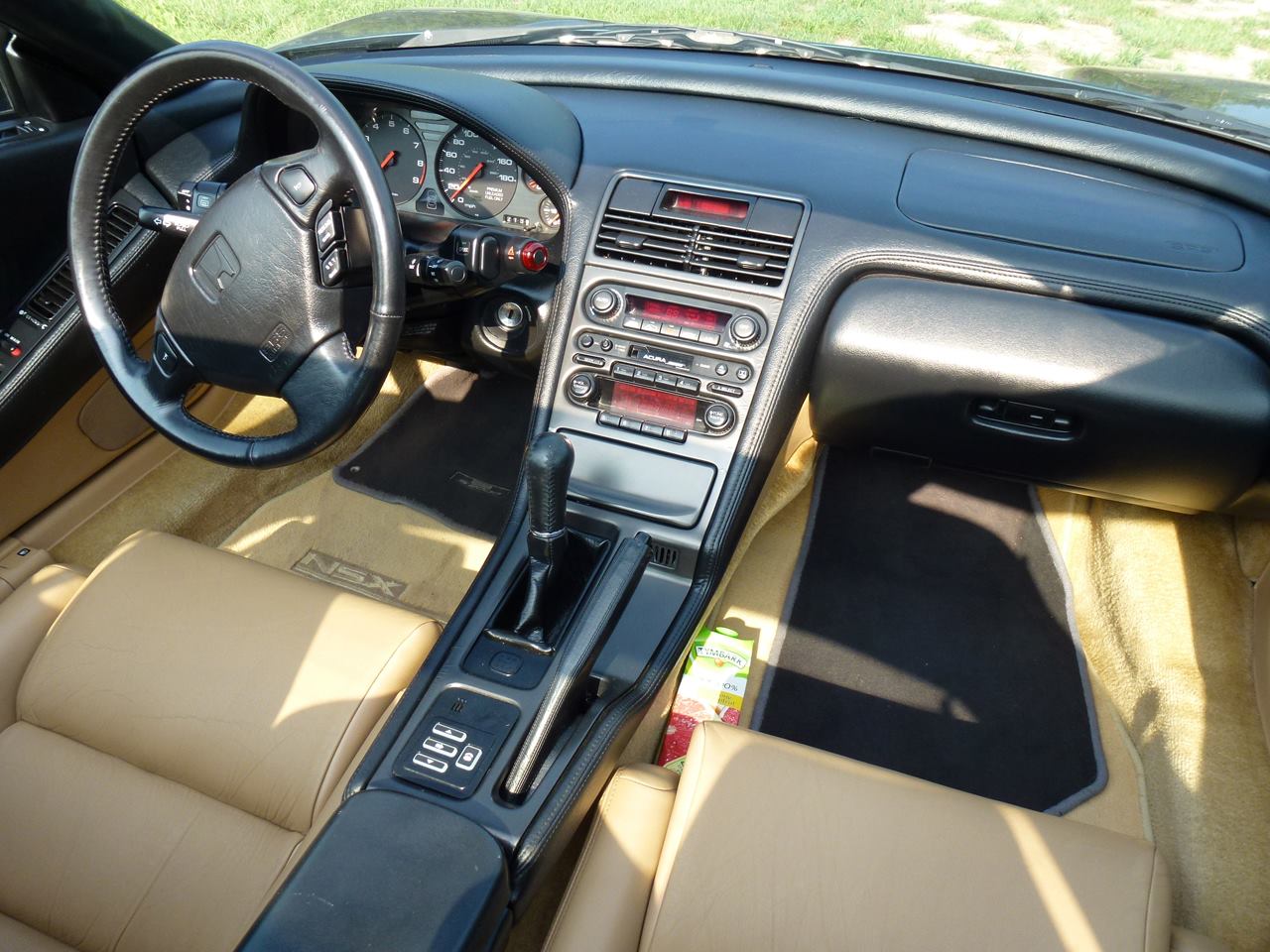 Honda NSX cockpit with tan leather seats, five-speed shifter, and wraparound dashboard
